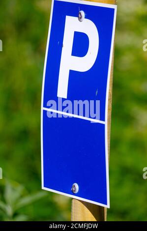 Blaues Parkschild mit einem großen P darauf und Grüner Hintergrund Stockfoto