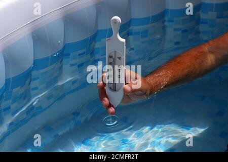 Thermometer, das die Temperatur des Schwimmbeckenwassers überprüft Stockfoto