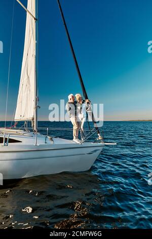 In voller Länge schöne ältere Paar in der Liebe auf dem Meer reisen, stehen sie auf der Seite des Segelboots oder Yacht Deck schwimmend im Meer Stockfoto