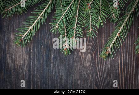 Weihnachtsbaumzweige aus Fichte auf gealtertem Holzhintergrund angeordnet Stockfoto