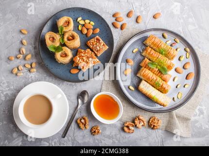 Set von verschiedenen traditionellen arabischen Süßigkeiten: Baklava, kunafa, Basbus in Keramikplatten auf grauem Betongrund. Draufsicht, flach liegend. Stockfoto