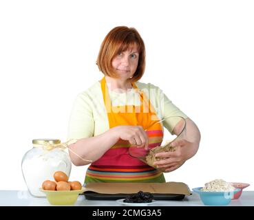 Porträt einer hübschen blauäugigen Frau mittleren Alters in einer hellen Schürze, die Cookie macht. Stockfoto