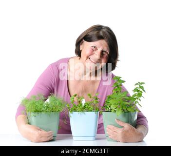 Die hübsche Frau umarmte ihren Ruhestand drei Töpfe mit Sämlingen. Stockfoto