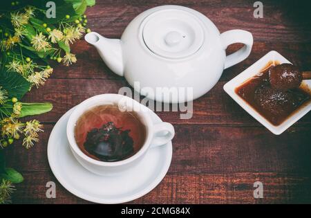 Weiße Tasse heißer schwarzer Tee, Teekanne und Honig von Linde Stockfoto