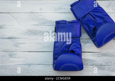 Ein Paar blaue Boxhandschuhe auf einer weißen Holzoberfläche Stockfoto