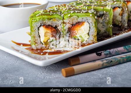 Sushi setzt Nigiri, Uramaki, California, Philadelphia, auf einen weißen Teller. In der Nähe Ingwer und Wasabi. Sojasauce in einer weißen Schüssel. Auf hellgrauem Hintergrund Stockfoto