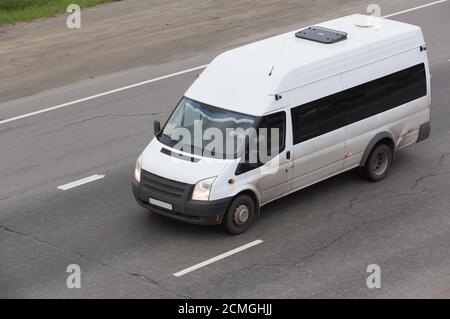 Minibus geht auf Landstraße entlang des Waldes Stockfoto