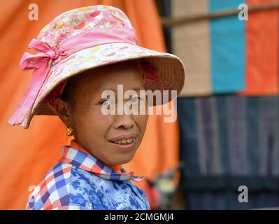 Ältere vietnamesische Hmong ethnische Minderheit Hügel-Stamm Frau trägt einen modernen Sonnenhut in rosa und lächelt für die Kamera. Stockfoto