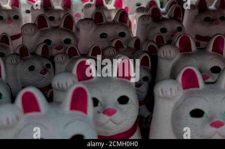 Nahaufnahme schattige Ansicht von vielen japanischen Maneki-Neko 'winkende Katze' Figuren, am Gotokuji Tempel in Tokyo Stockfoto