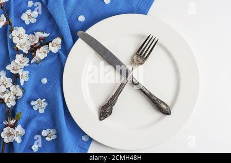 Gekreuzte Messer und Gabel auf einer leeren weißen Platte Stockfoto