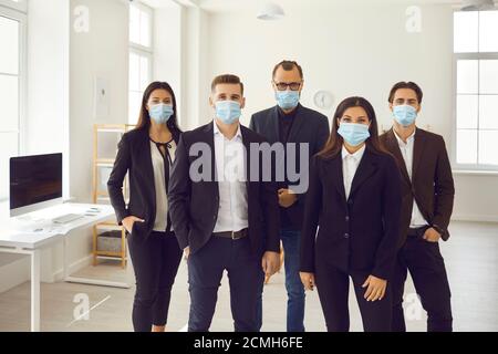 Gruppe von jungen Firmenmitarbeitern kümmern sich um Kunden und tragen Medizinische Gesichtsmasken bei der Arbeit Stockfoto