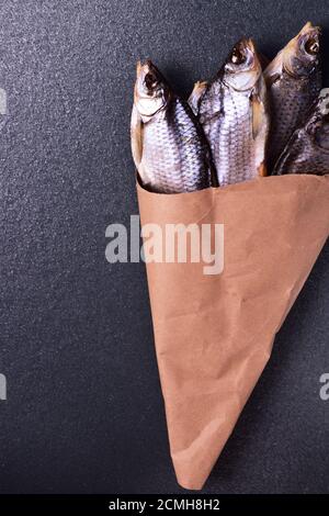 Getrockneter Fisch in einem Beutel mit Papier auf eine schwarze Fläche Stockfoto