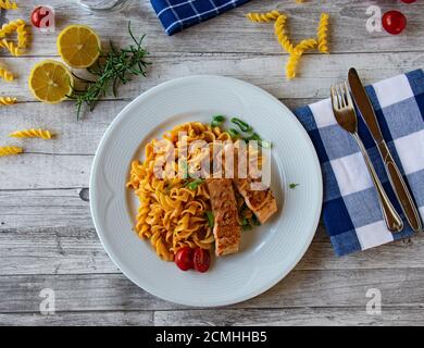Pasta mit Lachs auf weißem Teller serviert auf Holz Hintergrund Stockfoto