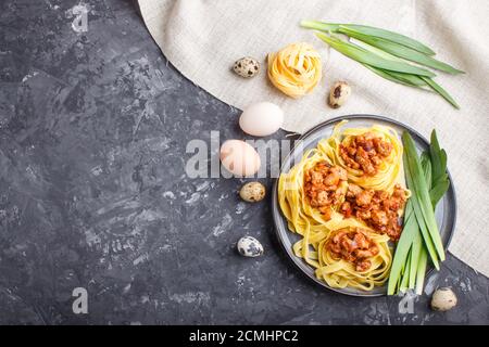 Tagliatelle Bolognese Pasta mit Hackfleisch auf schwarzem Beton-Hintergrund. Draufsicht, flach liegend, Kopierraum. Stockfoto