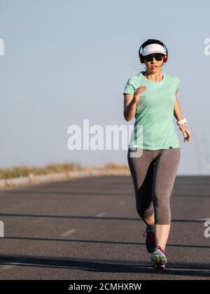 Frau, die auf der Straße läuft und Musik hört Stockfoto