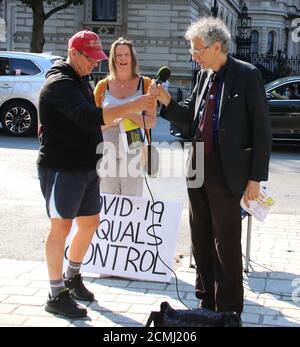 Piers Corbyn hält ein Mikrofon, bevor er mit einer Menschenmenge gegenüber den Toren der Downing Street spricht.der freimütig agierende Piers Corbyn - Bruder des ehemaligen Arbeiterführers Jeremy Bernard Corbyn wurde gesehen, wie er gegenüber der Downing Street kämpfte und mit einer Menschenmenge über seine Covid-19 Verschwörungstheorie sprach. Er kam in Westminster mit mehreren Kampagnen Plakate, nach denen er traf mit anderen Aktivisten in Whitehall. Der Astrophysiker hat sich an Menschenmengen während der Sperre behauptet, Covid-19 Ausbruch wurde entwickelt, um die Bevölkerung zu kontrollieren. Stockfoto