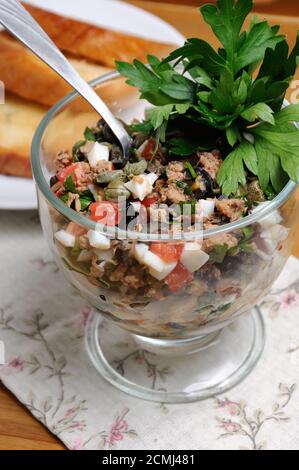 Gehackter Thunfisch mit Ei, Würfel von Tomaten und Oliven Scheiben, Kapern und Petersilie. Salat in ein Glas. Stockfoto