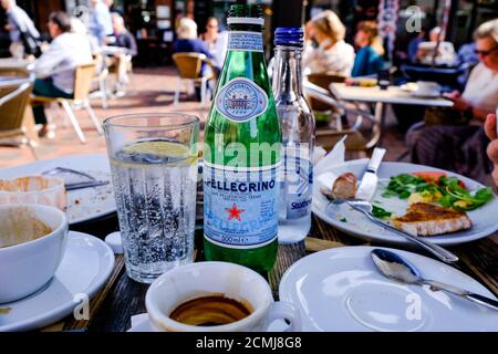 Frühstückstisch Mit Essen Und Flaschen Wasser Mit Leeren Kaffeetassen, Ohne Personen Stockfoto