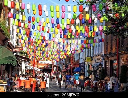 Die Menschen gehen unter bunten Regenbogenlaternen, die die Straßen von Chinatown aufgehellt haben.Chinatown London hat in Partnerschaft mit der London Chinatown Chinese Association (LCCA) die ikonischen roten Laternen der Gegend durch Tausende von speziellen Regenbogenlaternen ersetzt. Die Reihen von bunten Laternen in den Straßen von Chinatown sind Teil der Kampagne #LoveChinatown, um die Gemeinschaft der Chinatown-Unternehmen zu unterstützen und Menschen sicher in der Gegend willkommen zu heißen. Der Regenbogen war auch ein Symbol für die Unterstützung während der gesamten Pandemie für die wunderbaren Schlüsselarbeiter des Vereinigten Königreichs. Stockfoto