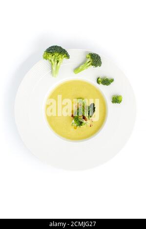 Weißer Teller mit Brokkoli-Sahne-Suppe, serviert mit Pinienkernen auf hellem Hintergrund. Stockfoto