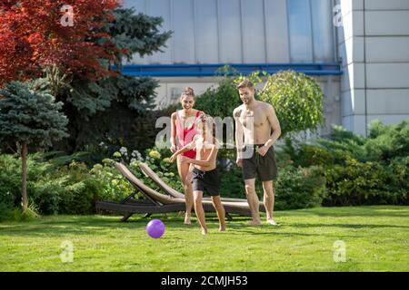 Sohn und Eltern in Badeanzügen laufen nach dem Ball Stockfoto