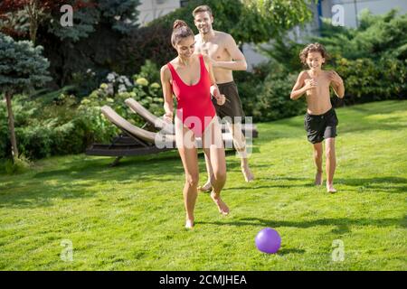 Mama läuft nach Ball Papa mit Sohn hinter Stockfoto