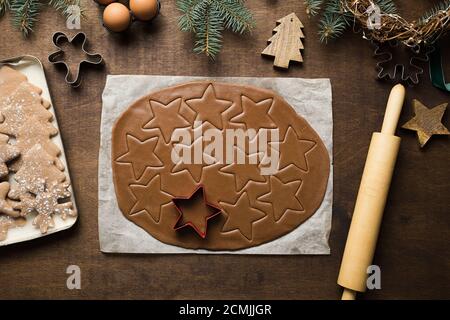 Gerollt ungekochten Teig Vorbereitung für festliche Weihnachtsleckereien auf Küchentisch dekoriert immergrünen Ästen und Cookies Cutter. Blick von oben. Weihnachten t Stockfoto