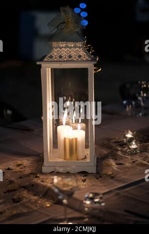 Vorbereitung mit Laternen, Kerzen und beleuchtet und Kerzenleuchter für die Hochzeit Geburtstagsfeier auf weißem Tischtuch in der Nacht. Hochwertige Fotos Stockfoto