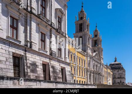 Weitwinkelansicht des königlichen Palastes der Mafra (Mafra, Portugal). In der Mitte ist die Basilika von zwei Glockentürmen und an der Seite zwei große Squa flankiert Stockfoto