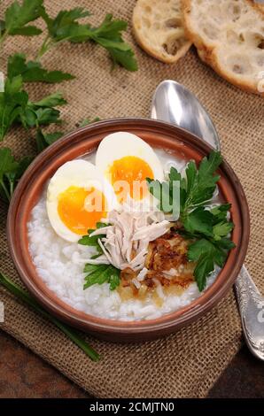 Reis Brei Ingwer Congee mit Ei, Huhn, knusprigen Schalotten und Petersilie Stockfoto