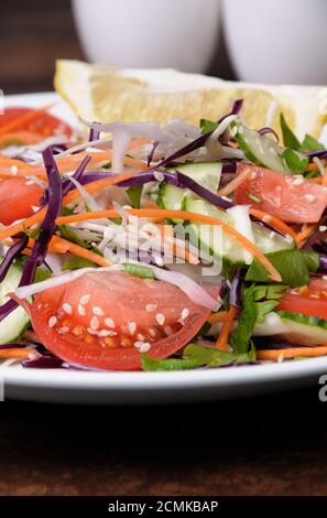 Salat aus weißen und blauen gehackten Kohl, Karotten, Gurken, Tomaten gekleidet mit Öl, Zitrone, Sesam Stockfoto