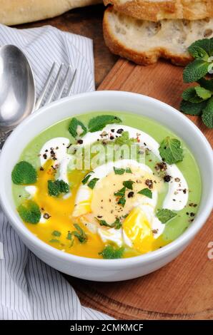 Püree Erbsensuppe mit pochiertem Ei, saure Sahne, Minze Blätter mit Gewürzen gewürzt. Stockfoto