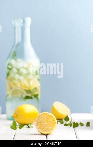 Reife Zitronen und Minzblätter vor dem Hintergrund einer Flasche Limonade. Stockfoto