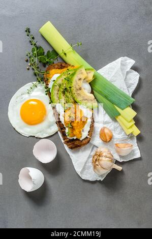 Sandwich mit Avocado, Paprikapaste und Spiegeleier auf einem grauen Steintisch. Stockfoto