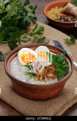 Reis Brei Ingwer Congee mit Ei, Huhn, knusprigen Schalotten und Petersilie Stockfoto