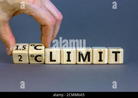 Symbol für die Begrenzung der globalen Erwärmung. Hand dreht einen Würfel und ändert den Ausdruck '2 oC Limit' in '1.5 oC Limit' oder umgekehrt. Wunderschöner grauer Hintergrund Stockfoto