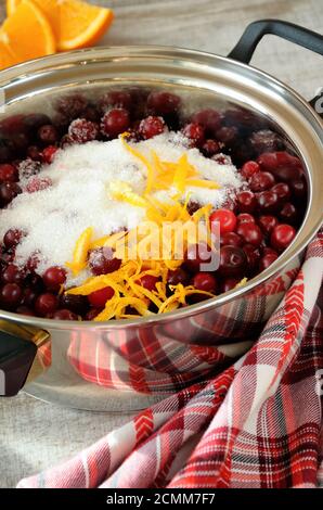 Frische Cranberries mit Zucker und Zitronenschale in einem Topf abgedeckt Stockfoto