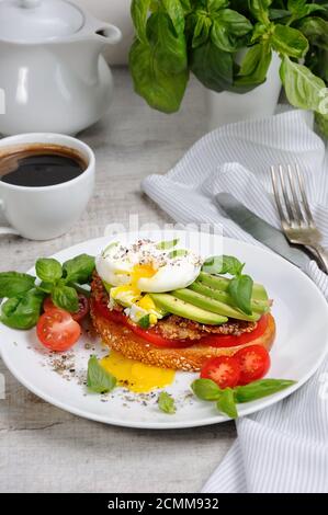 Ei pochiert auf einer gerösteten Scheibe Baguette mit Tomaten, würzigem Schinken und Avocado, bestreut Gewürze und Stockfoto