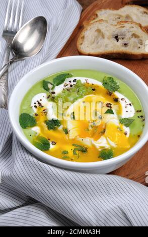 Püree Erbsensuppe mit pochiertem Ei, saure Sahne, Minze Blätter mit Gewürzen gewürzt. Stockfoto