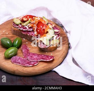 Sandwich mit geräucherter Wurst und Gemüse auf einem Küche Holzbrett, Ansicht von oben Stockfoto