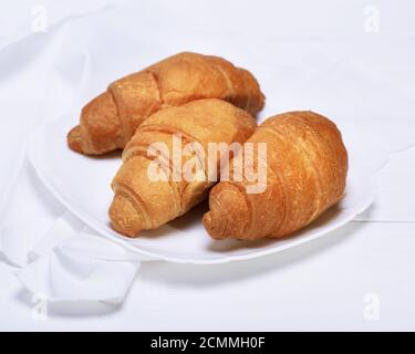 Drei frisch gebackene Croissants auf einem weißen Keramikplatte Stockfoto