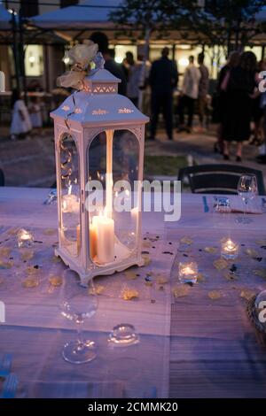 Vorbereitung mit Laternen, Kerzen und beleuchtet und Kerzenleuchter für die Hochzeit Geburtstagsfeier auf weißem Tischtuch in der Nacht. Hochwertige Fotos Stockfoto