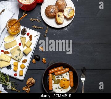 Spiegelei und Wurst in ein schwarzes Geschirr gusseisernen Pfanne, stücke Käse Stockfoto