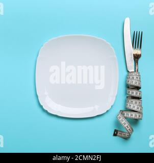 Messer mit einer Gabel in ein Maßband mit einer weißen Keramikplatte gewickelt Stockfoto