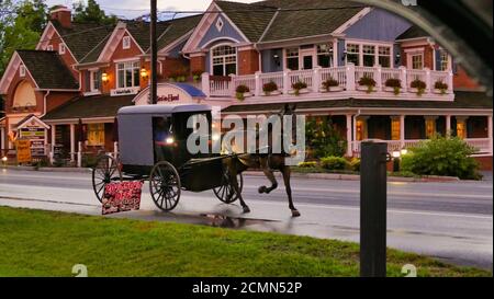 Amish Horse and Buggy Passing Stores auf einer Landstraße. Hochwertige Fotos. An einem späten Nachmittag Stockfoto