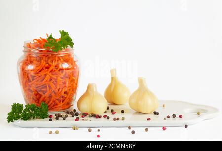 Glas fermentierte Karotten neben marinierten garlics auf weiß isoliert Hintergrund mit Kopierbereich Stockfoto