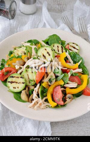 Warmer Hähnchensalat mit Spinat, Tomatenscheiben, Paprika, gegrillten Zucchini und Champignons, alles Stockfoto