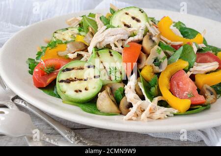 Warmer Hähnchensalat mit Spinat, Tomatenscheiben, Paprika, gegrillten Zucchini und Champignons, alles Stockfoto