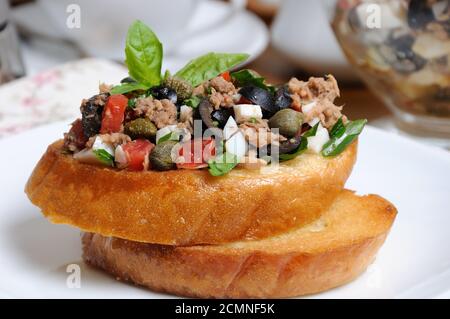 Gebratener Toast mit gehackten Thunfisch mit Ei, Würfeln Oliven Scheiben, Kapern und Tomaten Stockfoto