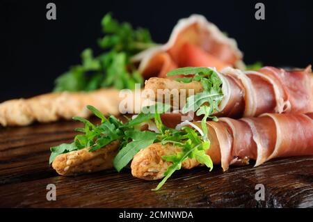 Grissini - Brotscheiben mit Parmesan, eingewickelt mit einem Stück Prosciutto und Rucola. Italienische DIS Stockfoto